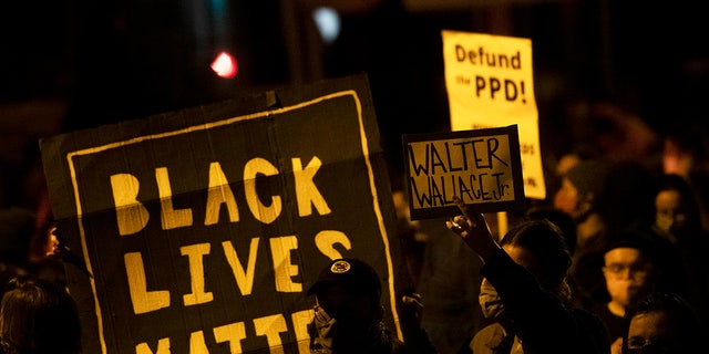 Demonstrators hold placards reading "Black Lives Matter," "Walter Wallace Jr." and "Defund the PPD" as they gather in protest on Oct. 27, 2020, in Philadelphia.