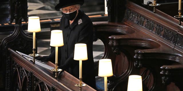 Queen Elizabeth II watches as Prince Philip, Duke of Edinburgh's casket is carried into St George's Chapel during the funeral of Prince Philip, Duke of Edinburgh at Windsor Castle on April 17, 2021 in Windsor, UK.  She had to sit alone because of the coronavirus policy. 