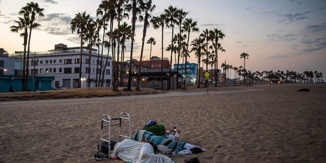 Two homeless people sleep on Venice Beach, California, on August 12, 2021.