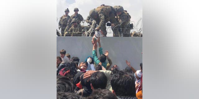 This image made available to AFP Aug. 20, 2021, by human rights activist Omar Haidari shows a U.S. Marine grabbing an infant over a fence of barbed wire during an evacuation at Hamid Karzai International Airport in Kabul Aug. 19, 2021.