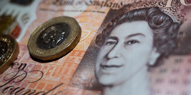 The British currency in the form of two one pound coins rests on a ten pound banknote from the Bank of England with the image of Queen Elizabeth II.