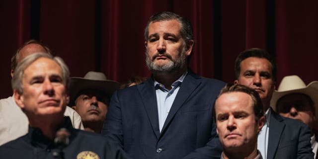 Texas Republican Senator Ted Cruz watches as Texas Gov. Greg Abbott speaks during a press conference at Uvalde High School in Uvalde, Texas, May 25, 2022.  