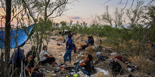 Migrants rest after crossing the Rio Grande River as they wait to get apprehended by Border Patrol agents as National Guard agents sit on a car across the street (out of frame), in Eagle Pass, Texas, at the border with Mexico on June 30, 2022. 
