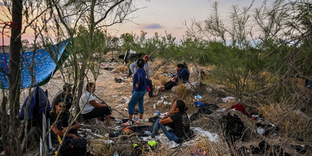 Migrants rest after crossing the Rio Grande River as they wait to get apprehended by Border Patrol agents as National Guard agents sit on a car across the street (out of frame), in Eagle Pass, Texas, at the border with Mexico on June 30, 2022. 