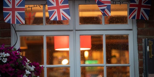 Union Jack flags hang on a pub window.  The number of pubs in England and Wales has dropped to an all-time low, according to a recent assessment. 