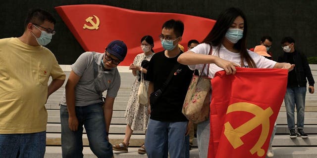 A woman folds a flag after posing for a picture at the Museum of the Communist Party of China in Beijing on September 4, 2022. (Photo by Noel Celis / AFP) (Photo by NOEL CELIS/AFP via Getty Images)