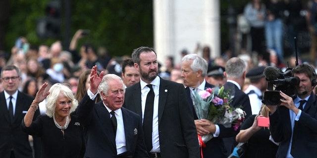 Britain's King Charles III and Camilla, Queen Consort, greet the crowd as they arrive at Buckingham Palace.