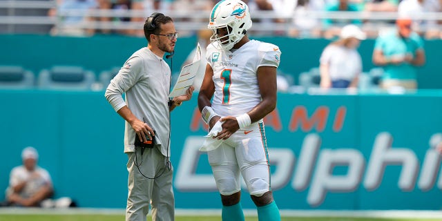 El entrenador en jefe de los Miami Dolphins, Mike McDaniel, habla con el mariscal de campo de los Miami Dolphins, Tua Tagovailoa (1), durante una interrupción del juego contra los New England Patriots el 11 de septiembre de 2022 en el Hard Rock Stadium en Miami Gardens, Florida.