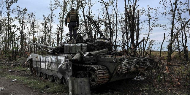 TOPSHOT - This photograph taken on September 11, 2022, shows a Ukranian soldier standing atop an abandoned Russian tank near a village on the outskirts of Izyum, Kharkiv Region.