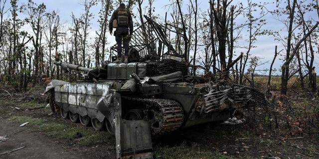 TOPSHOT - This photograph taken on September 11, 2022, shows a Ukranian soldier standing atop an abandoned Russian tank near a village on the outskirts of Izyum, Kharkiv Region.