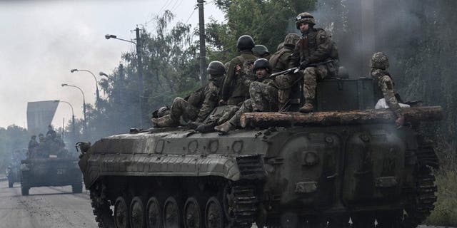 Ukrainian soldiers sit on infantry fighting vehicles as they drive near Izyum in eastern Ukraine on Sept. 16, 2022.