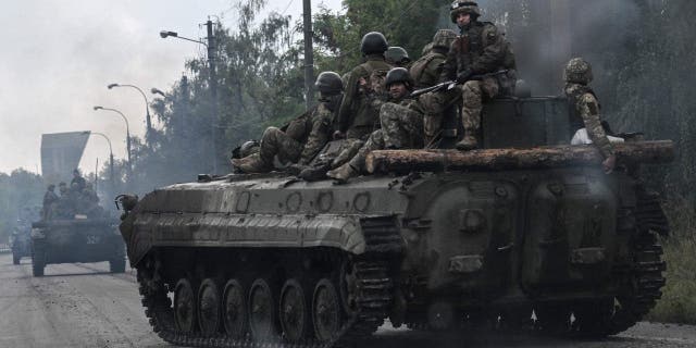 Ukrainische Soldaten sitzen auf Infanterie-Kampffahrzeugen, als sie am 16. September 2022 inmitten der russischen Invasion in der Ukraine in der Nähe von Izyum in der Ostukraine fahren.