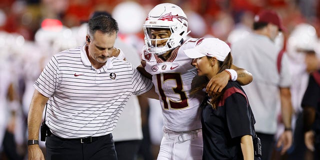 Florida State Seminoles quarterback Jordan Travis is helped off the field after suffering an injury while being sacked during a game against the Louisville Cardinals Sept. 16, 2022, at Cardinal Stadium in Louisville, Ky. 