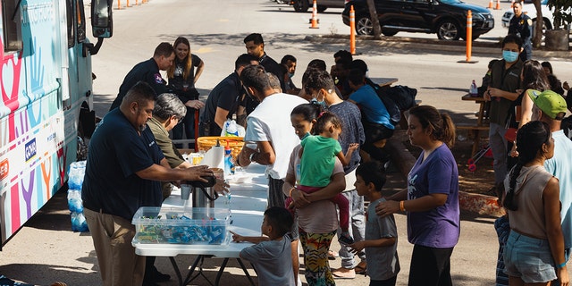 Groups of migrants wait outside the Migrant Resource Center to receive food from Catholic charities on September 19, 2022 in San Antonio, Texas.