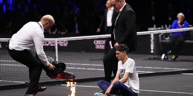 A protester lights a fire on the court on day one of the Laver Cup at the O2 Arena, London Friday, Sept. 23, 2022.