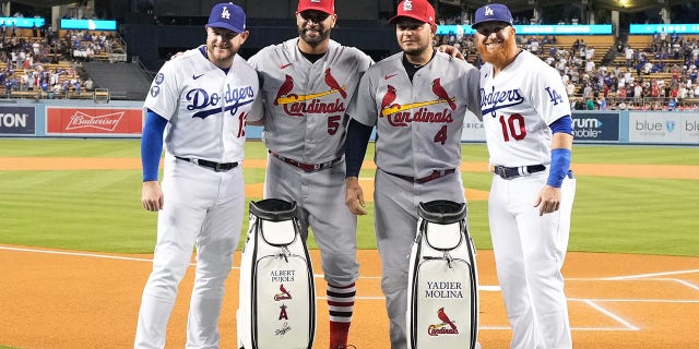 Albert Pujols (5) and Yadier Molina (4) of the St. Louis Cardinals pose with Max Muncy (13) and Justin Turner (10) of the Los Angeles Dodgers with golf bags gifted to them at Dodger Stadium in Los Angeles Friday, Sept. 23, 2022.