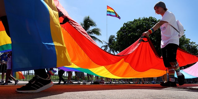 People carry the Rainbow Flag as they participate in the Miami Beach Pride Parade along Ocean Drive on September 19, 2021. 