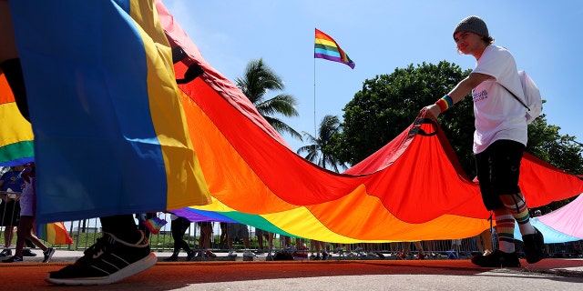 People carry the Rainbow Flag as they participate in the Miami Beach Pride Parade along Ocean Drive on September 19, 2021.