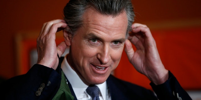 Democratic Gov. Gavin Newsom removes his mask before speaking during a press conference at the Native American Health Center in Oakland, California, on Dec. 22, 2021.