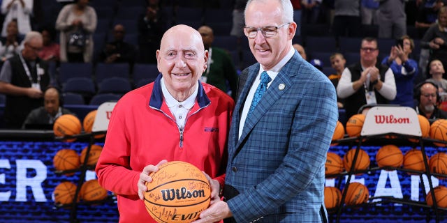 (L-R) College Basketball broadcaster Dick Vitale receives an autographed basketball from SEC Commissioner Greg Sankey prior to the start of the game between the Texas A&amp;amp;M Aggies and Arkansas Razorbacks in the Semifinal game of the SEC Men's Basketball Tournament at Amalie Arena on March 12, 2022 in Tampa, Florida. 