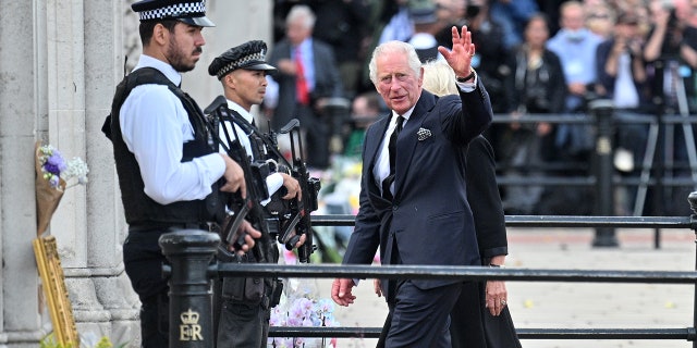 King Charles III waves to the public after viewing floral tributes to the late Queen Elizabeth II outside Buckingham Palace on Sept. 9, 2022 in London.