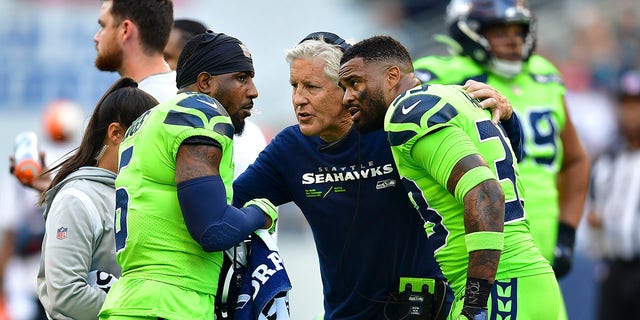 (L-R) Quandre Diggs, #6, head coach Pete Carroll and Jamal Adams, #33 of the Seattle Seahawks, at Lumen Field speak during the second quarter on Sept. 12, 2022 in Seattle. 