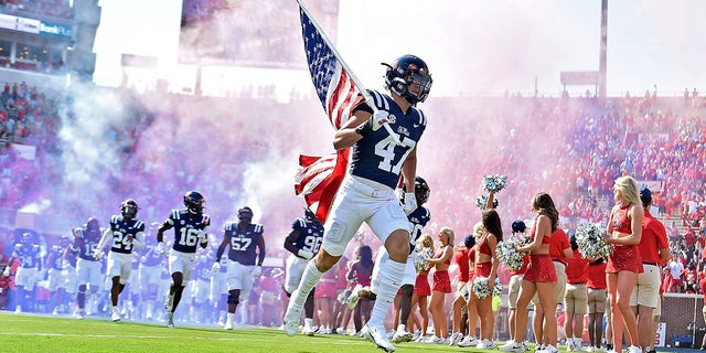 Trustin Northington of the Rebels holds an American flag during the Tulsa Golden Hurricane game at Vaught-Hemingway Stadium on Sept. 24, 2022 in Oxford, Mississippi.