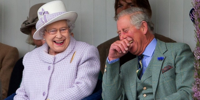 Queen Elizabeth II and Prince Charles, Prince of Wales laugh whilst watching the children's sack race as they attend the 2012 Braemar Highland Gathering.