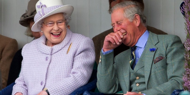 Queen Elizabeth II and Prince Charles, Prince of Wales laugh whilst watching the children's sack race as they attend the 2012 Braemar Highland Gathering.