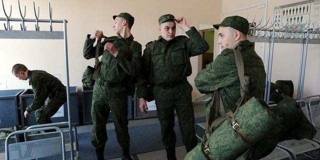 Russian army conscripts change into their uniforms at the military registration and enlistment office in St. Petersburg, April 22, 2014. Tens of thousands of Russian soldiers are massed on Ukraine's eastern border in this that NATO considers a state of invasion readiness. 
