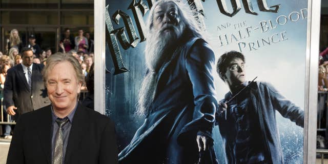 Alan Rickman, who played Snape, stands in front of an advertisement for a Harry Potter movie.