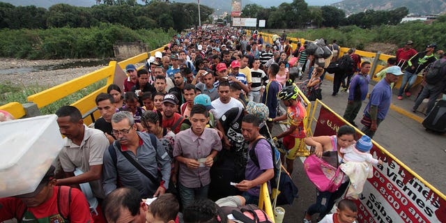TOPSHOT - Venezuelan citizens cross the Simon Bolivar international bridge from San Antonio del Tachira in Venezuela to Norte de Santander province of Colombia on February 10, 2018. Oil-rich and once one of the wealthiest countries in Latin America, Venezuela now faces economic collapse and widespread popular protest.  / AFP PHOTO / GEORGE CASTELLANOS        (Photo credit should read GEORGE CASTELLANOS/AFP via Getty Images)