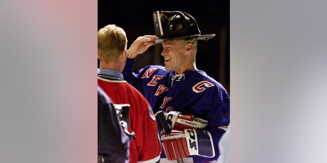 New York Rangers' captain Mark Messier puts on the helmet of Fire Department Chief of Special Operations Command Ray Downey at Madison Square Garden on Oct. 7, 2001. 