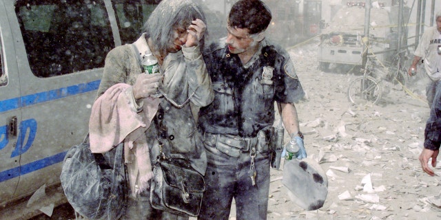 Police officer Mike Brennan helps a distraught woman known only as Beverly, as ash and debris cover the area following the collapse of 1 World Trade Center.