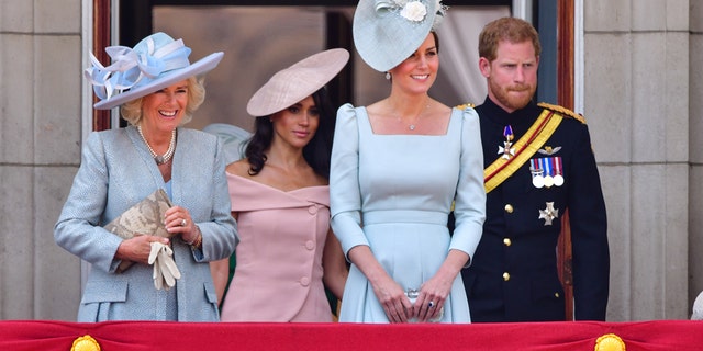 Отляво: кралица-консорт Камила (тогава херцогиня на Корнуол);  Меган, херцогиня на Съсекс;  Катрин, принцеса на Уелс (тогава херцогиня на Кеймбридж);  и принц Хари, херцог на Съсекс, стоят на балкона на Бъкингамския дворец по време на парада Trooping the Color в Лондон на 9 юни 2018 г.
