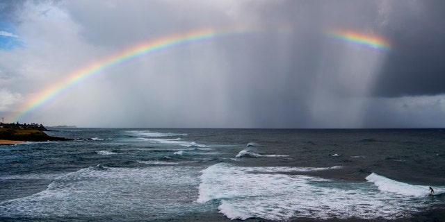 Some believe that seeing a repeated pattern of numbers or seeing certain symbols such as a rainbow mean that a guardian angel is visiting. In this photo from Hawaii, a rainbow graces the sky over Hookipa beach as a surfer catches a wave on a break called Pavilions, along the north shore of Maui. 