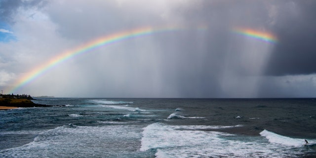 Some believe that seeing a repeated pattern of numbers or seeing certain symbols such as a rainbow mean that a guardian angel is visiting. In this photo from Hawaii, a rainbow graces the sky over Hookipa beach as a surfer catches a wave on a break called Pavilions, along the north shore of Maui. 