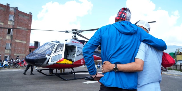 Jim Morrison, second right, mourns as the body of his partner and famed US extreme skier Hilaree Nelson arrives in a helicopter at a hospital in Kathmandu, Nepal, on Wednesday.