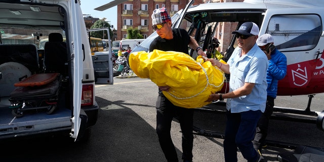 Jim Morrison carries the body of his partner and famed US extreme skier Hilaree Nelson from a helicopter at a hospital in Kathmandu, Nepal, on Wednesday.