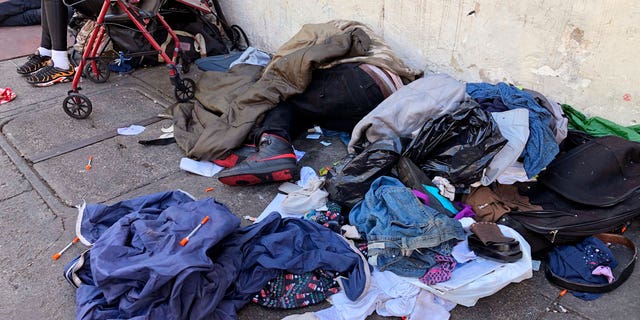 People sleep near discarded clothing and used needles on a street in the Tenderloin neighborhood in San Francisco.