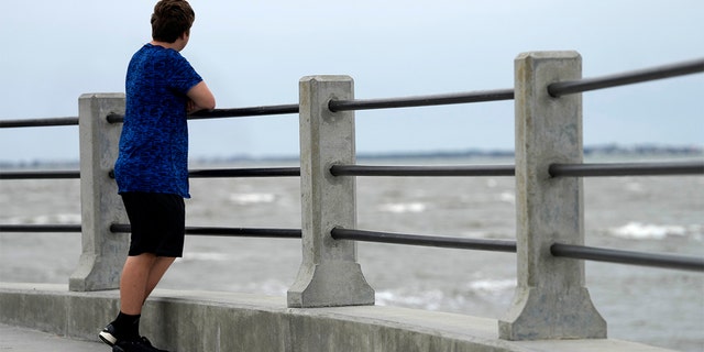 A boy looks out at Charleston Harbor as winds from Hurricane Ian begin to roll in to the Charleston, South Carolina, area on Thursday, Sept. 29, 2022. 