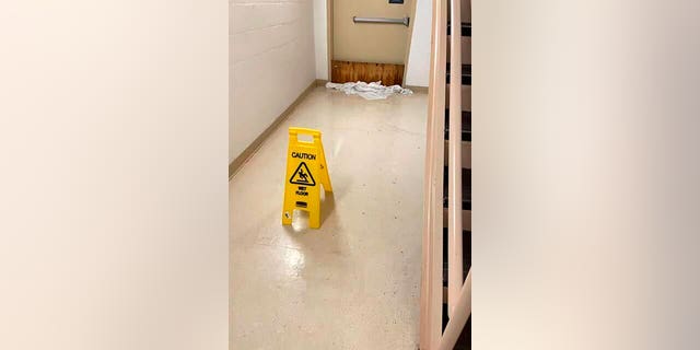 In this photo provided by Dr. Birgit Bodine, a cautionary sign is displayed in a wet hallway at HCA Florida Fawcett Hospital in Port Charlotte, Fla., Wednesday, Sept. 28, 2022. Hurricane Ian swamped the Florida hospital from both above and below, the storm surge flooding its lower level emergency room while fierce winds tore part of its fourth floor roof from its intensive care unit, according to Bodine, who works there. (Dr. Birgit Bodine via AP)