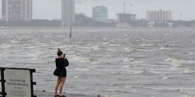 A woman takes photos of the surf on Tampa Bay ahead of Hurricane Ian, Wednesday, Sept. 28, 2022, in Tampa, Fla.