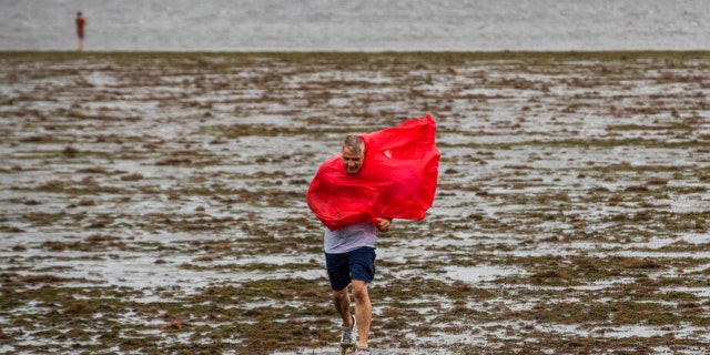 Curious sightseers walk in the receding waters of Tampa Bay due to the low tide and tremendous winds from Hurricane Ian in Tampa, Florida, Wednesday, Sept. 28, 2022. 