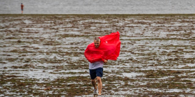 Curious sightseers walk in the receding waters of Tampa Bay due to the low tide and tremendous winds from Hurricane Ian in Tampa, Florida, Wednesday, Sept. 28, 2022.