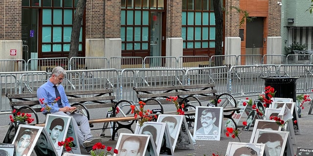 Nasser, president of the California Society for Democracy in Iran, sits in Dag Hammarskjold Park across from the U.N., surrounded by the photos of victims of the regime's "death commission."