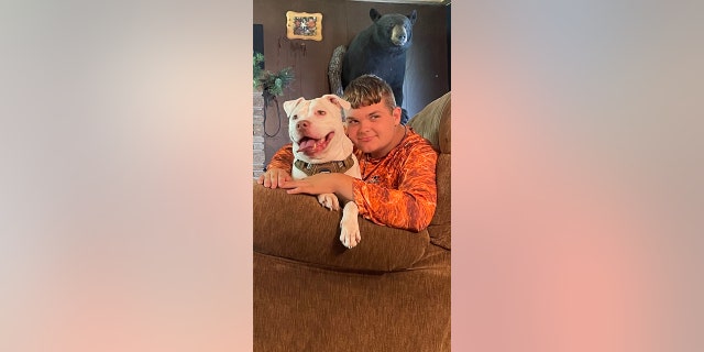 Walker Cousineau, a ninth-grade student, relaxes at home with Dave, his newly adopted dog. Walker is 14 and is experiencing hearing loss caused by a kidney disorder. Dave, his pit bull, is deaf.