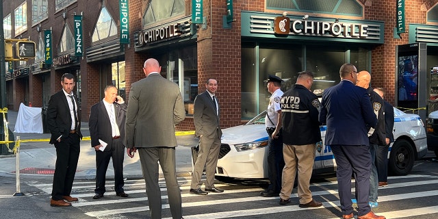 NYPD detectives stand outside a Chipotle near where a 25-year-old woman was fatally shot.