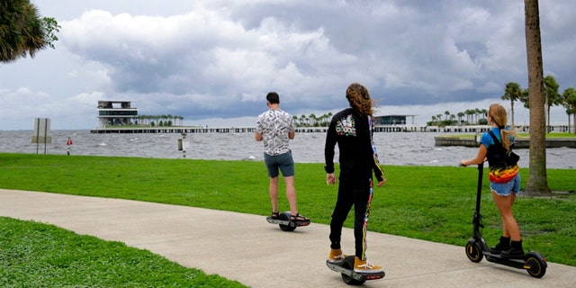 People ride along the bayfront as an outer band of Hurricane Ian approaches and kicks up the surf at Vinoy Park, Tuesday, Sept. 27, 2022, in St. Petersburg, Florida. 