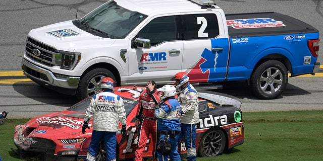 Chase Briscoe (14) is helped away from his car after wrecking along the front stretch after coming out of Turn 4 during a NASCAR Cup Series auto race at Daytona International Speedway, Sunday, Aug. 28, 2022, in Daytona Beach, Fla.